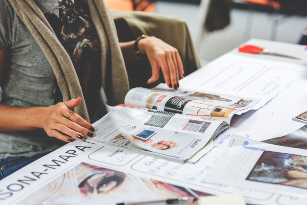 Mulher folheando revistas, que são formas de melhorar a comunicação interna e externa.