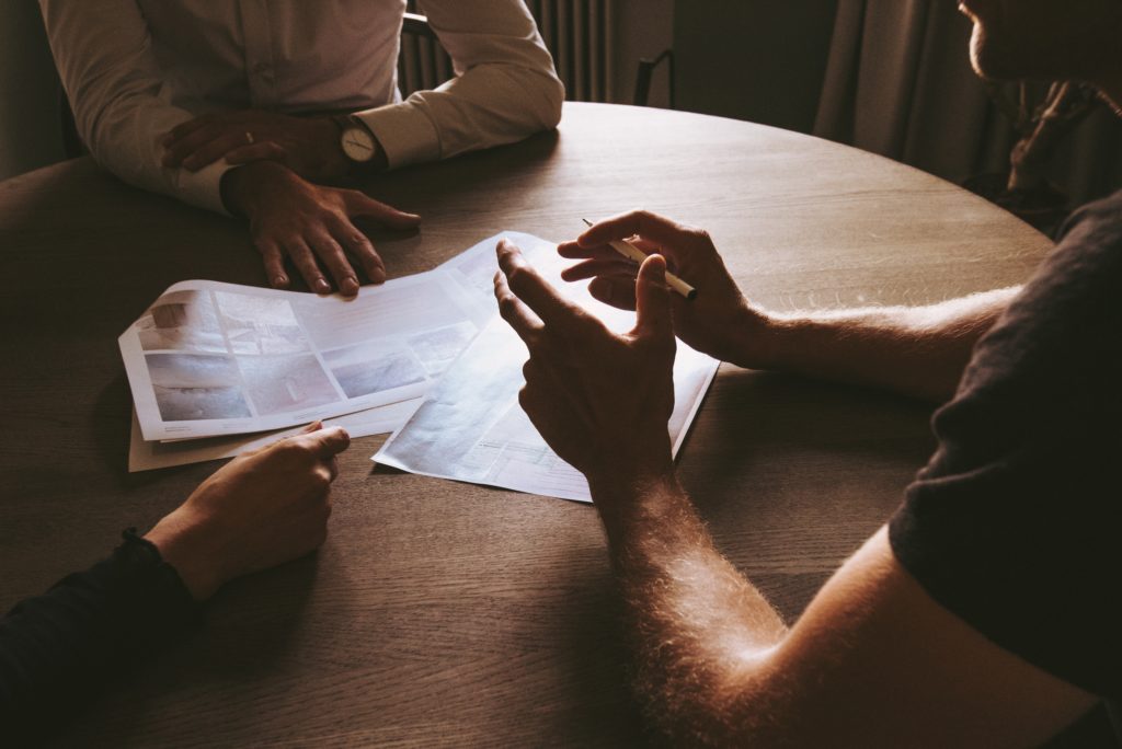 3 pessoas reunidas em volta de uma mesa circular pensando em como atrair clientes para a empresa.