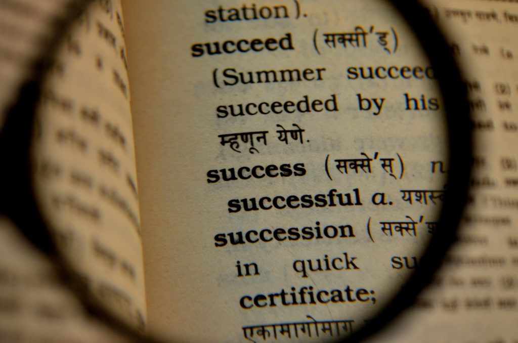 Lente de aumento sobre um dicionário destacando a palavra "success"