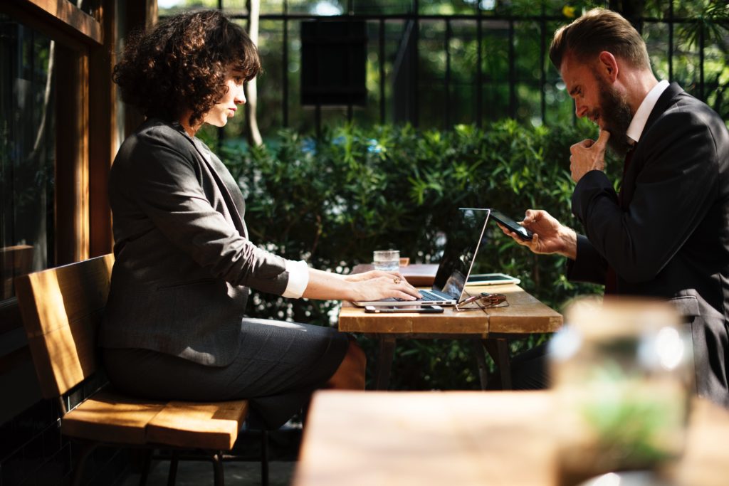 Um homem e uma mulher empresários sentados em volta de uma mesa com um notebook discutindo sobre crescimento empresarial