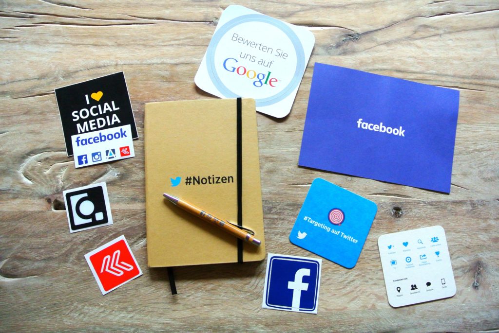 Diversos cadernos e papéis com a temática de redes sociais sobre uma mesa