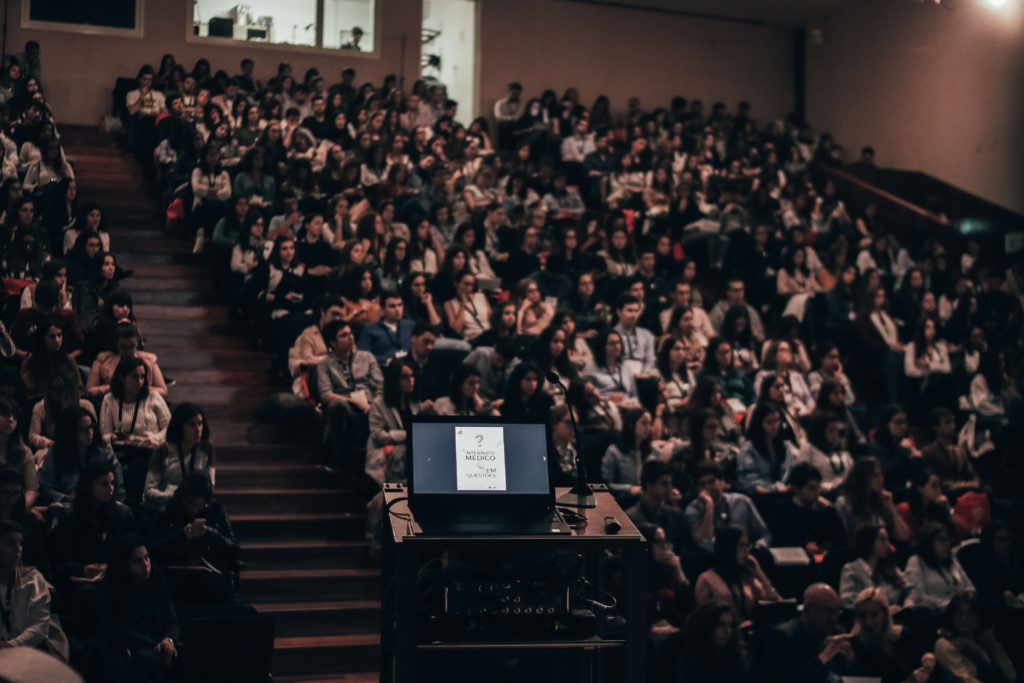 Auditório lotado de pessoas durante um evento corporativo.