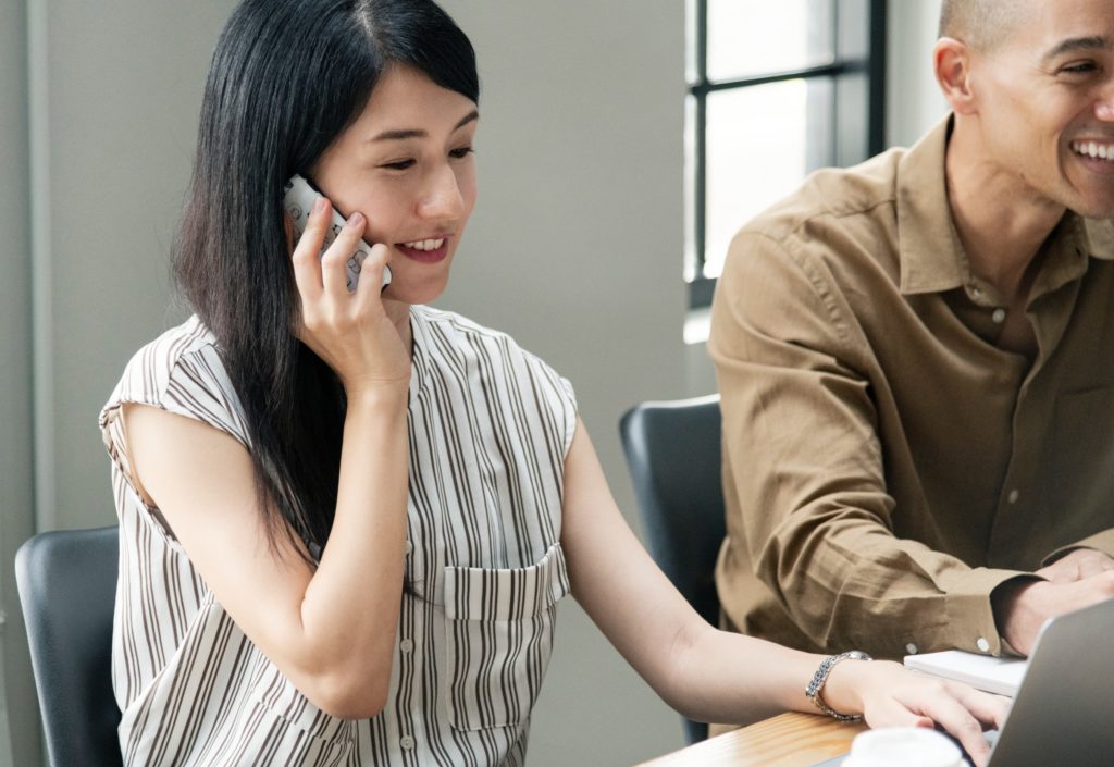 Empresária em escritório falando ao telefone celular.