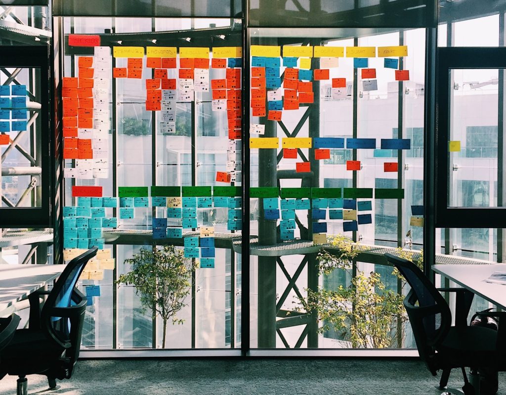 Uma porta de vidro com vários post-its colados, remetendo à criatividade de empresas