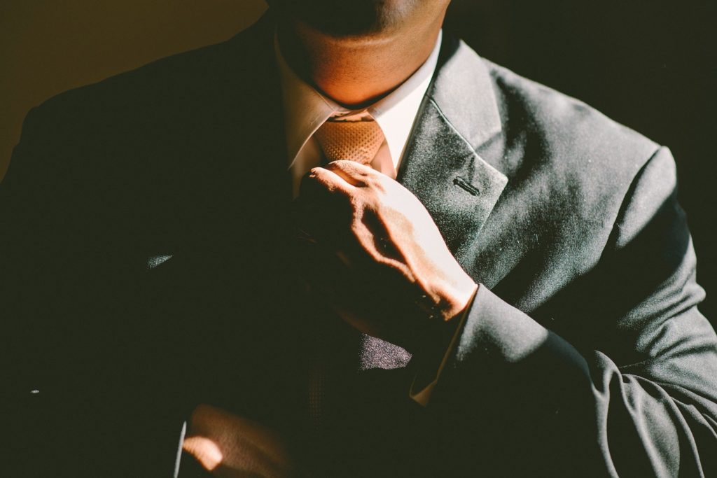 Um homem ajeitando sua gravata com o intuito de transmitir uma boa imagem pessoal em sua rede de relacionamento