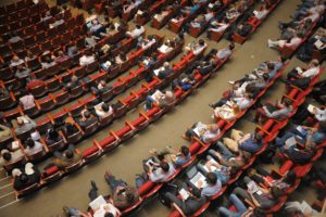 Várias pessoas sentadas em um grande auditório durante um evento corporativo.