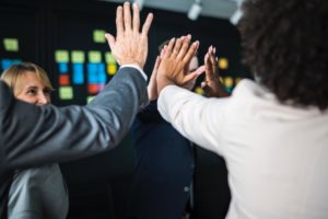 Pessoas batendo as mãos em sinal de parceria e fortalecendo a culltura da empresa